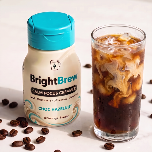 BrightBrew Calm Focus Creamer — bottle with cream-and-teal swirl label beside a tall clear glass of iced coffee with cream swirling in
